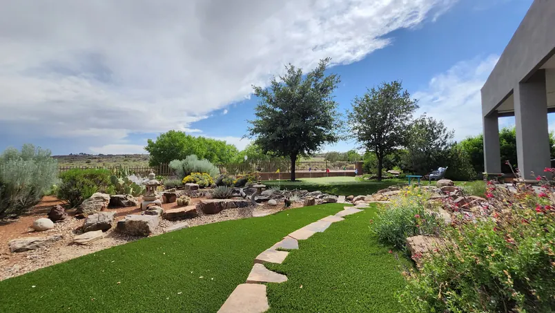 Landscaped grounds with a flagstone path through artificial grass and boulders