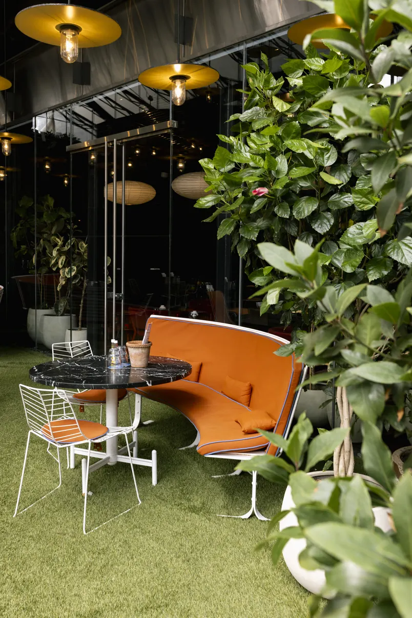 Restaurant patio seating framed by greenery and artificial turf
