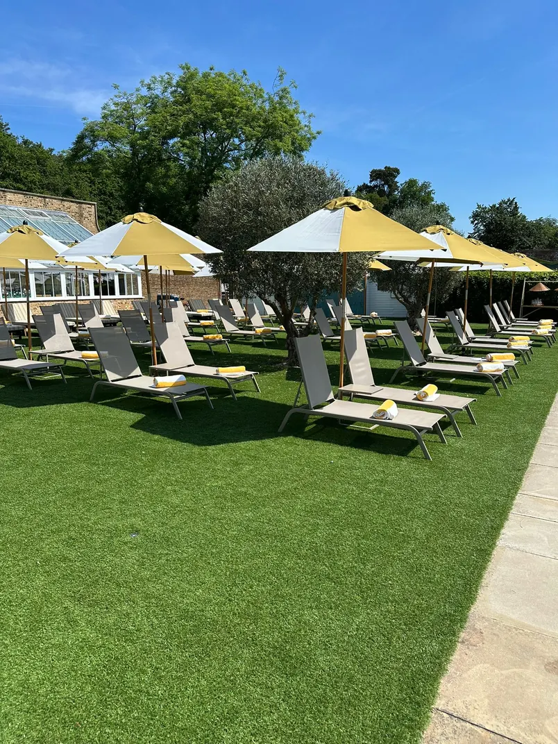Resort pool deck with lounge chairs and umbrellas on artificial grass