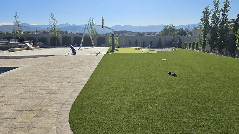 Landscaped backyard with a flagstone path winding through artificial grass and boulders