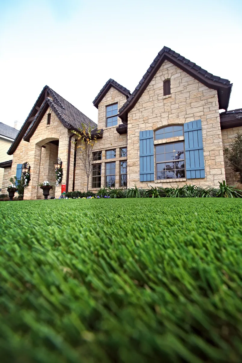 Stone house with a lush artificial lawn in the foreground