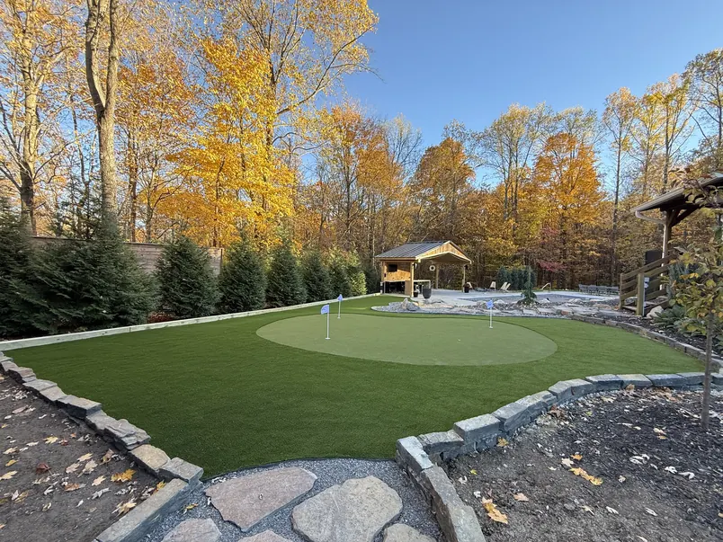 Backyard putting green framed by autumn trees and a gazebo