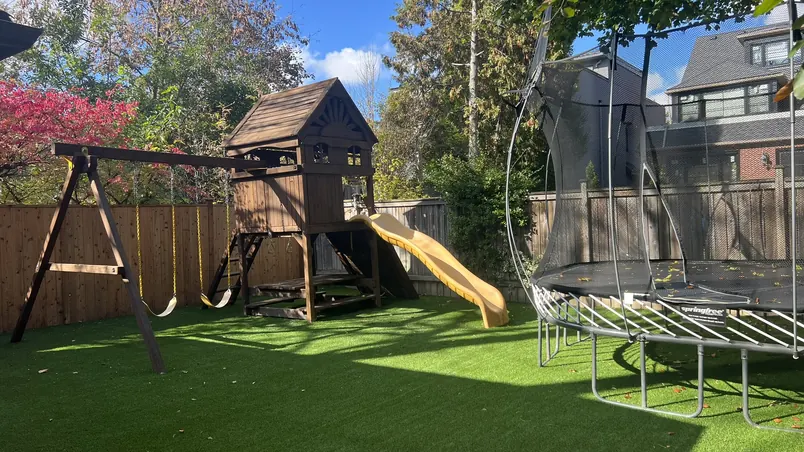 Wooden playset with a yellow slide on artificial turf
