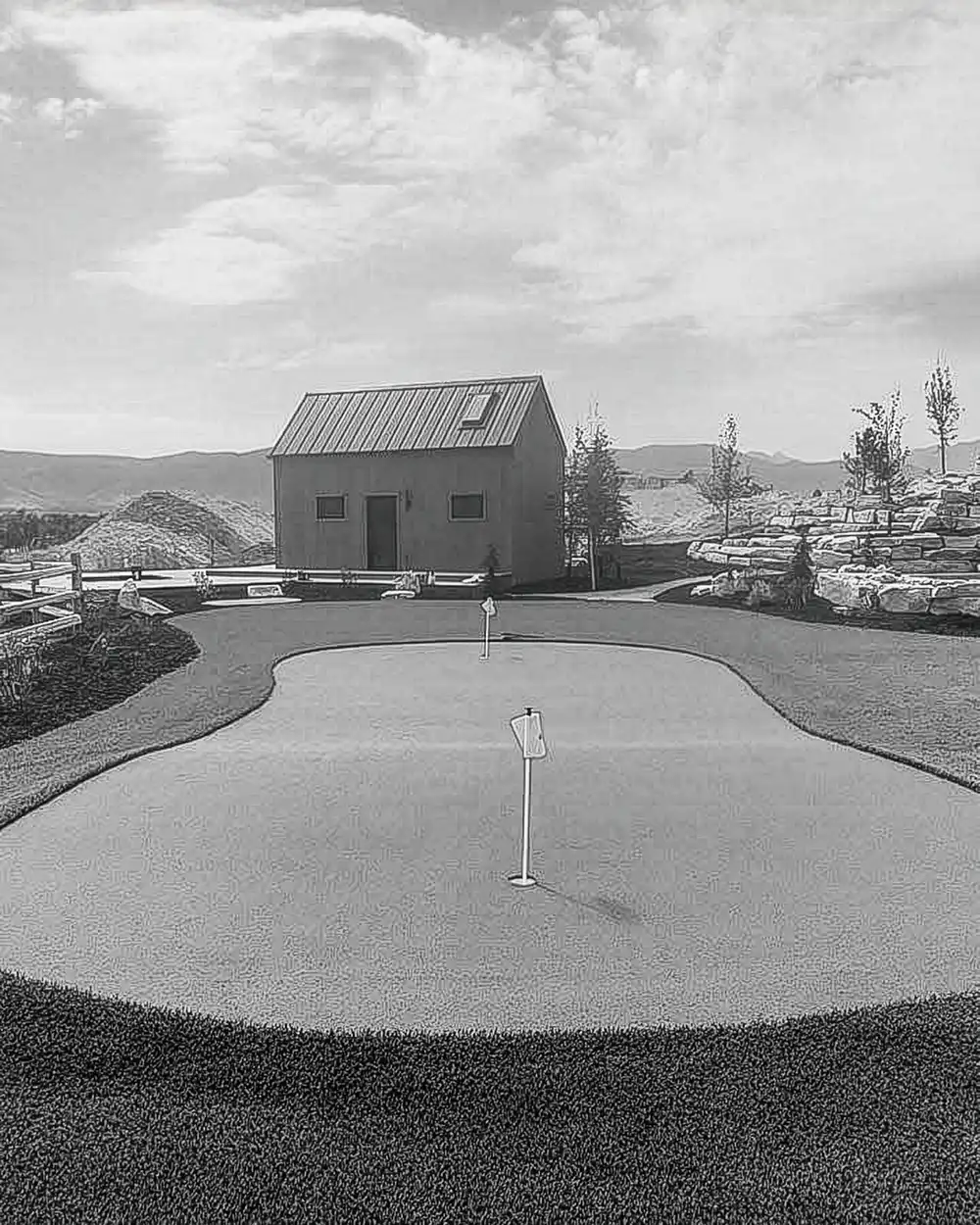 Backyard putting green with a flag in front of a small barn-style building